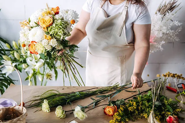 A florist arranging stems at a workbench