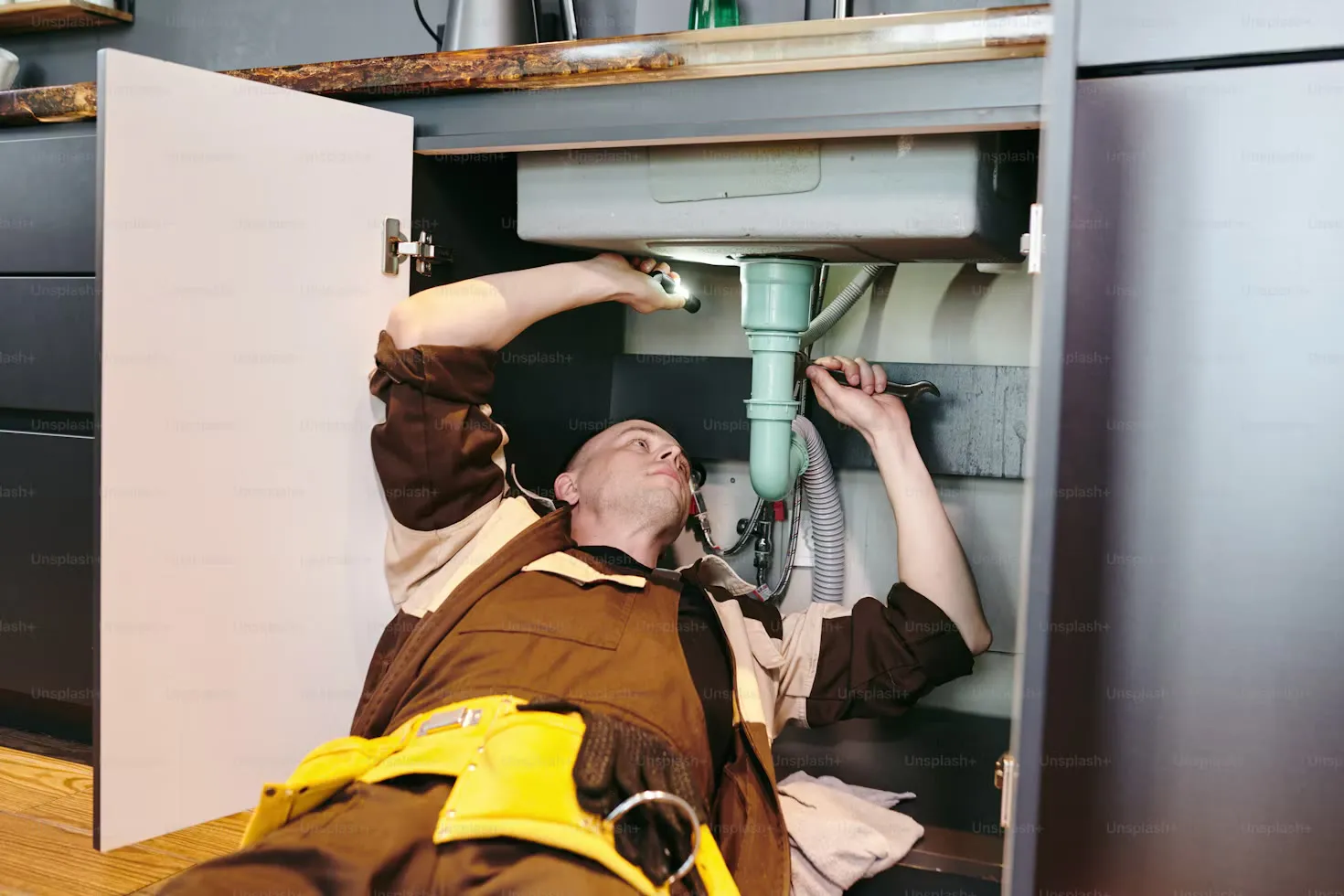 Pipework under a sink being checked for a leak